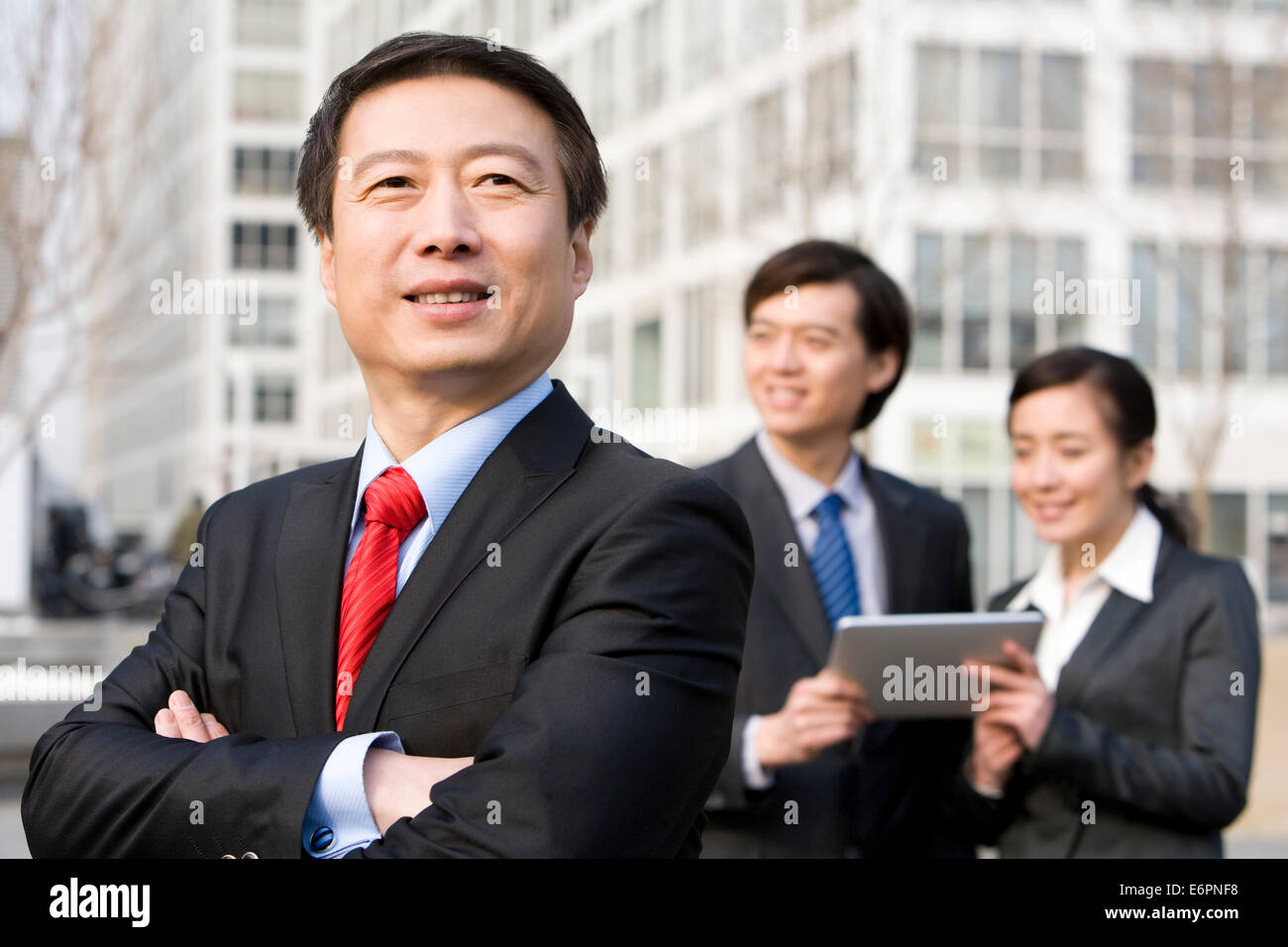 Older business man standing in front of colleagues Stock Photo