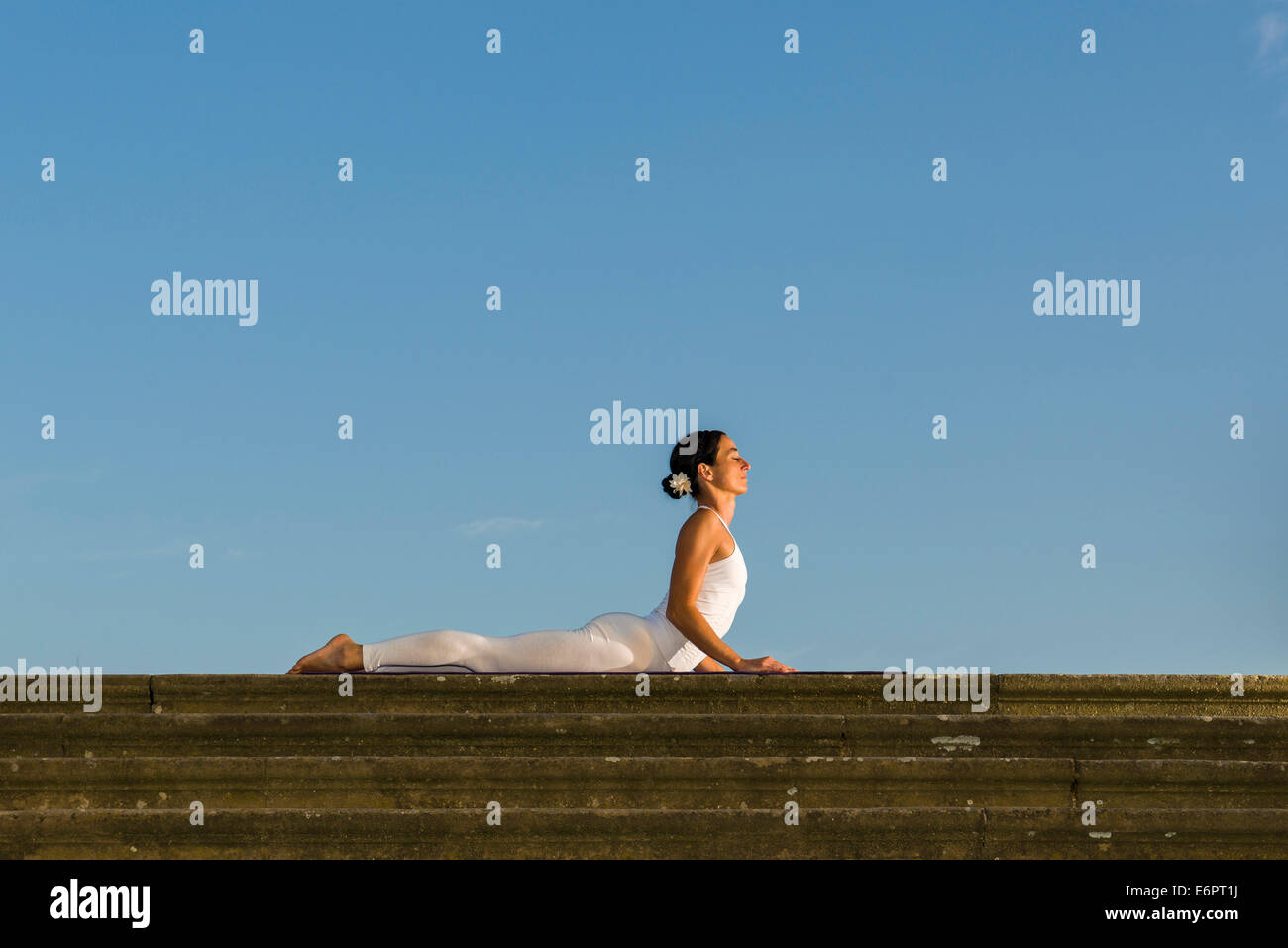 Young woman practising Hatha yoga, outdoors, showing the pose ...