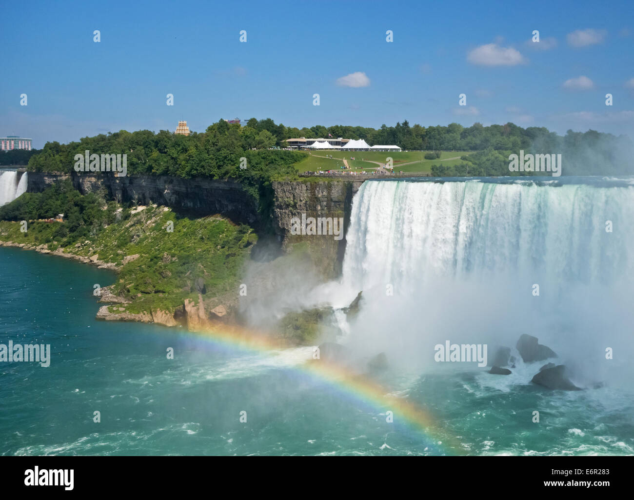 Horseshoe Falls in Niagara Falls with rainbow in the mist.  View from Canadian side of the visitor park on the American side. Stock Photo