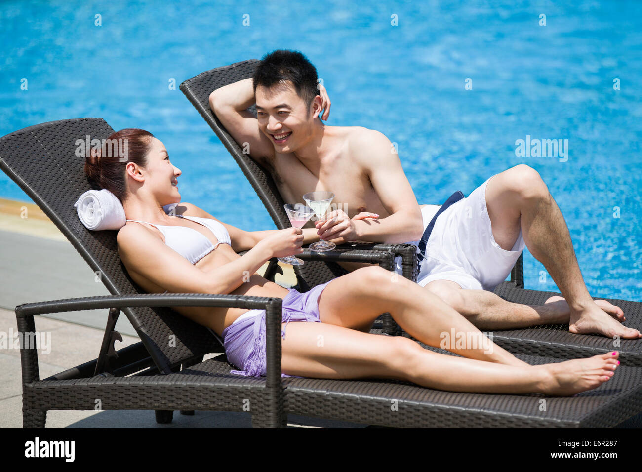 Young couple sunbathing at the poolside Stock Photo