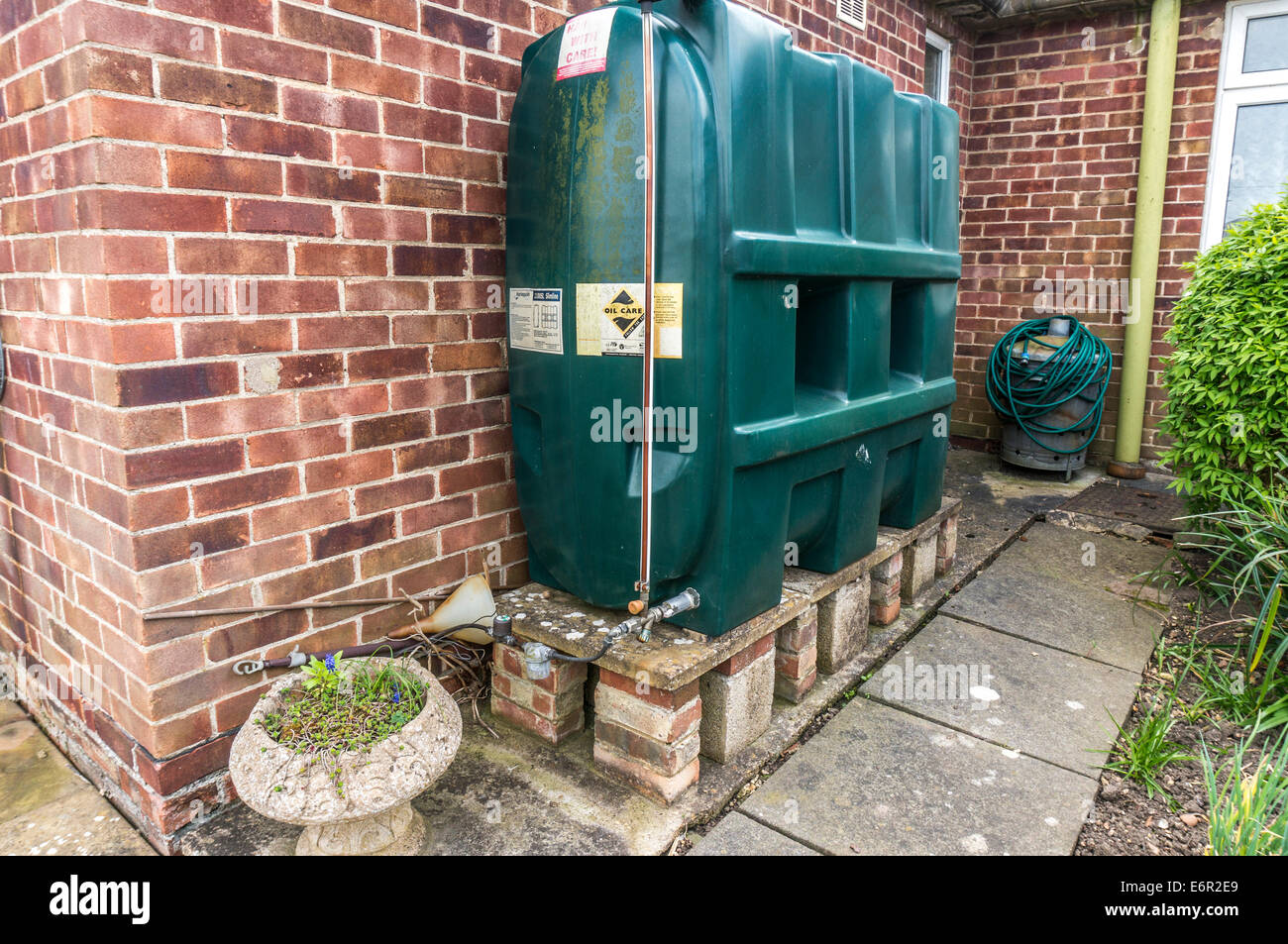 A domestic plastic oil tank, standing on a platform, above ground, next to a property, in a back garden in Northborough, Cambridgeshire, England, UK. Stock Photo