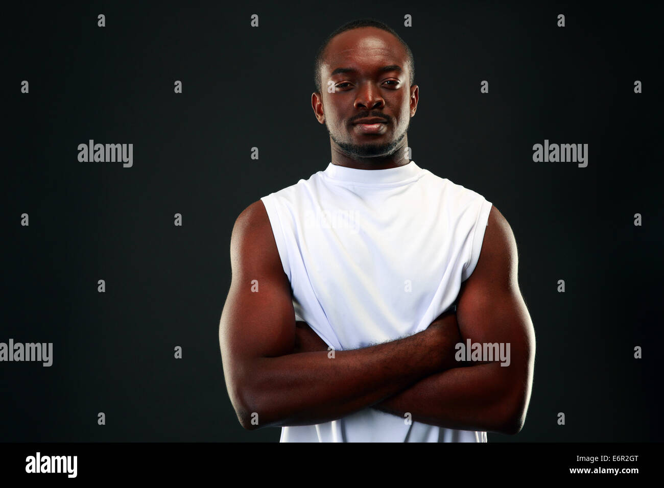 Portrait of a happy african man with arms folded over black background ...