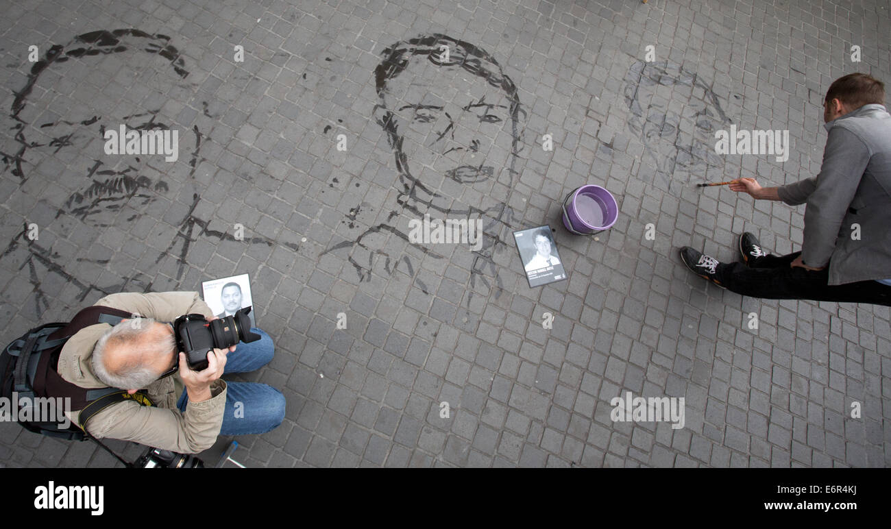 Activists take part in an art action to draw attention to forced disappearance with faces of people who have disappeared, Juan Almonte Herrera (L-R, Dominican Republic) and Hector Rangel Ortiz (Mexico), painted in water on the sidewalk in Berlin, Germany, 29 August 2014. Amnesty International is calling attention to victims of forced disapperance. Every year thousands of people worldwide are captured and taken to unknown locations on state orders or in cooperation with the state. Photo: JOERG CARSTENSEN/dpa Stock Photo