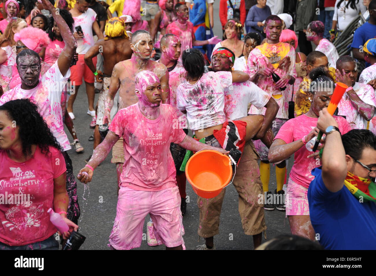 Crowd of people covered in pick and white paint at Notting Hill Carnival on family day Stock Photo