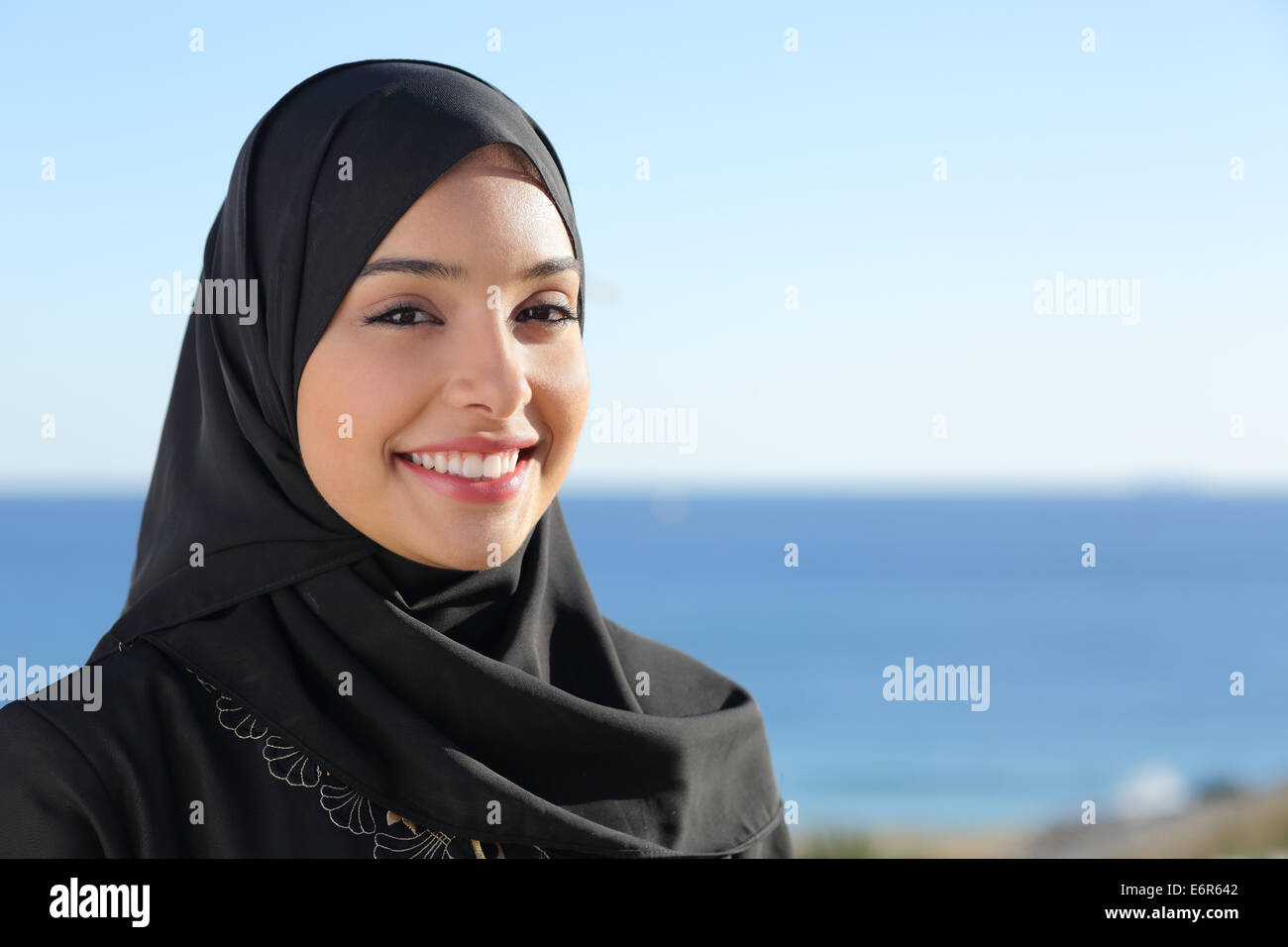 Beautiful arab saudi woman face posing on the beach with the sea in the background Stock Photo