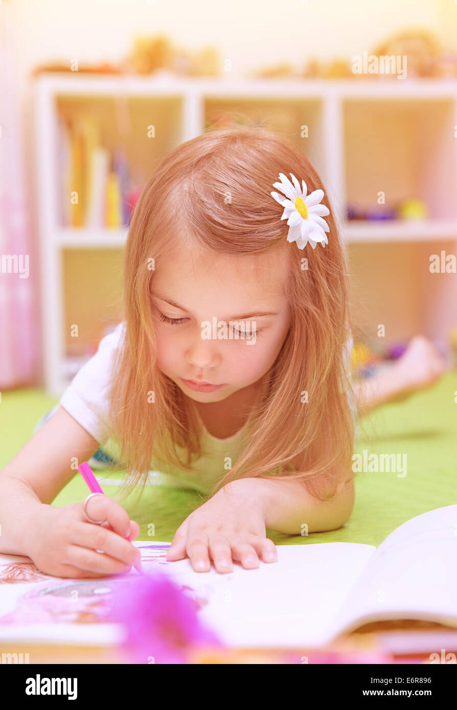 Cute little girl lying down on the floor and drawing picture to the ...