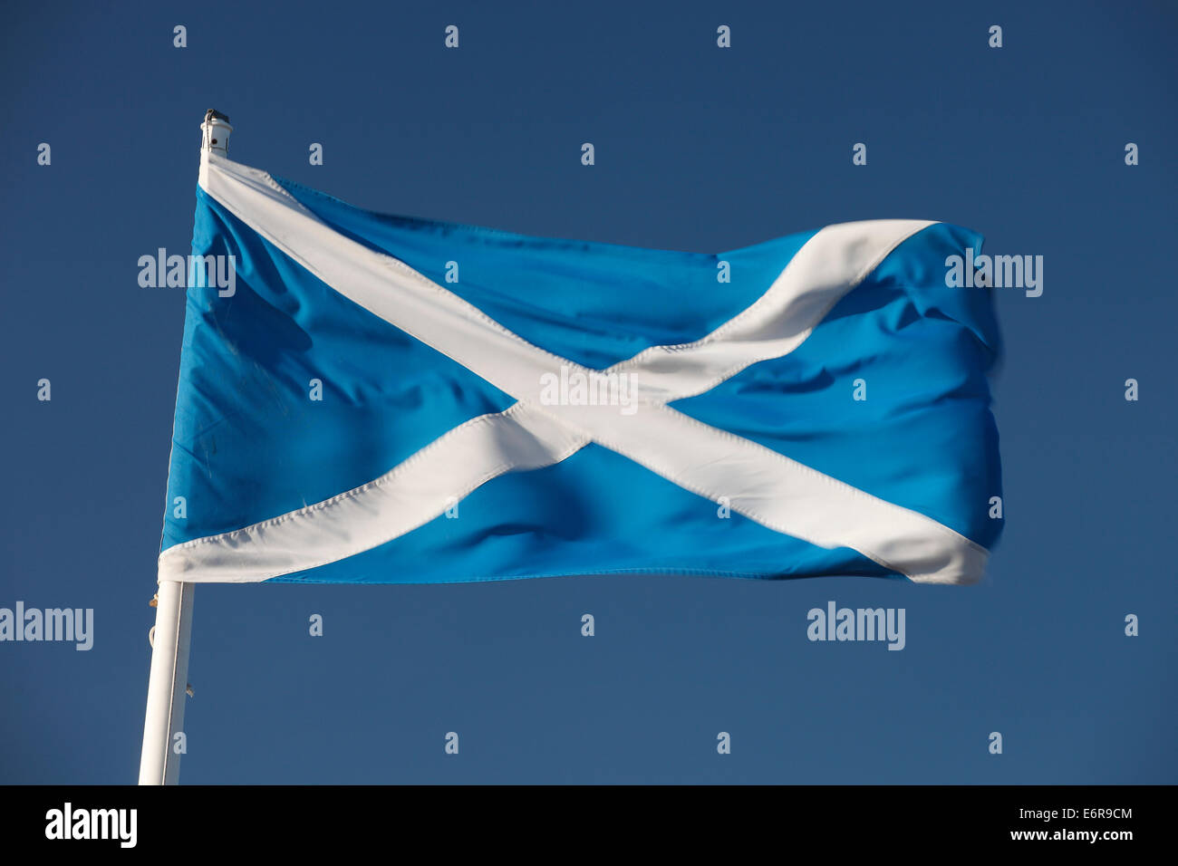 Scottish flag saltire cross of st andrew flapping in the breeeze against a deep blue sky. Stock Photo