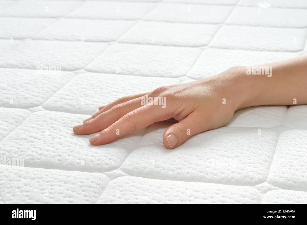 Choosing mattress and bed. Close-up of female hand touching and testing mattress in a store. Copy space. Stock Photo