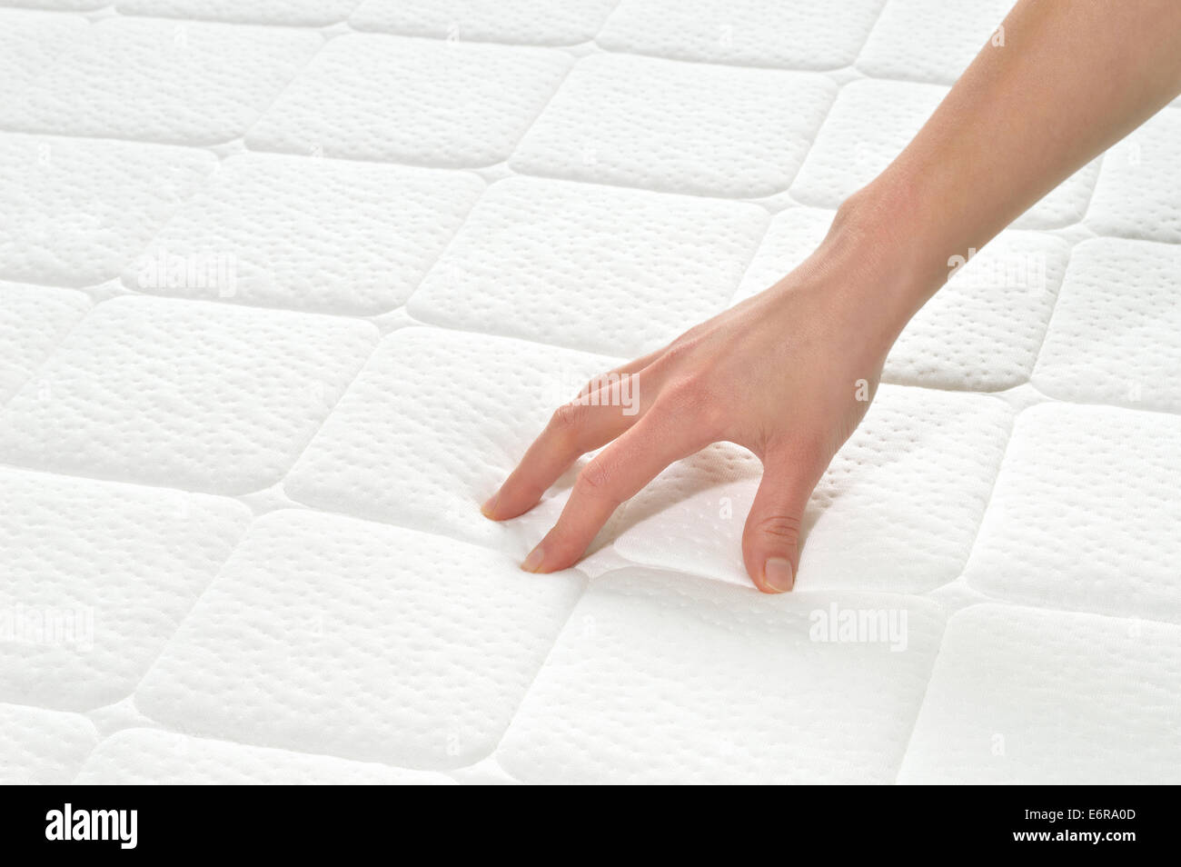 Choosing mattress and bed. Close-up of female hand touching and testing mattress in a store. Copy space. Stock Photo