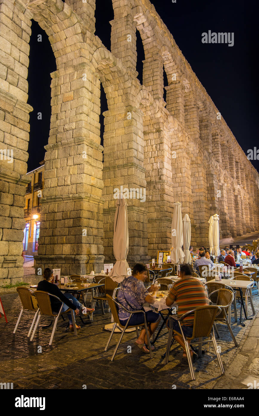 Night view of an outdoor restaurant with Roman aqueduct bridge behind, Segovia, Castile and Leon, Spain Stock Photo