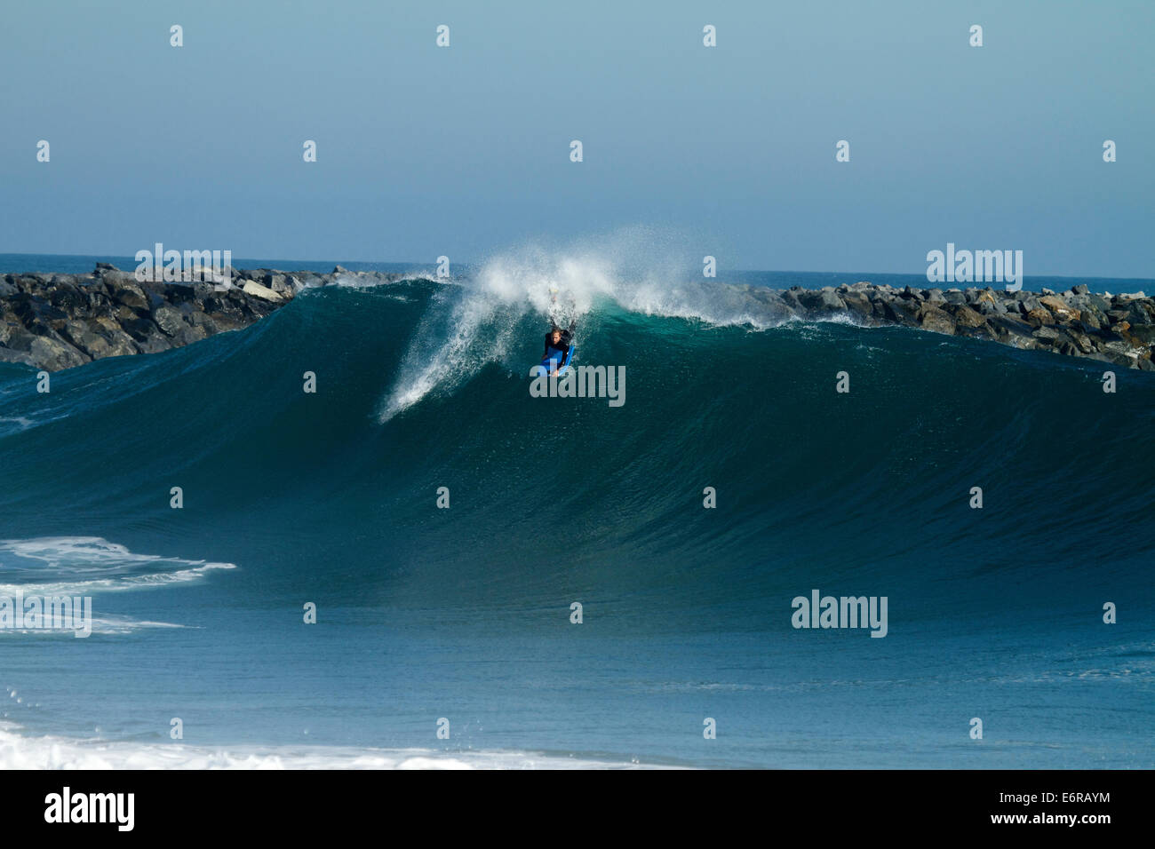Surfers riding a bodyboard the huge surf created by Hurricane Marie in