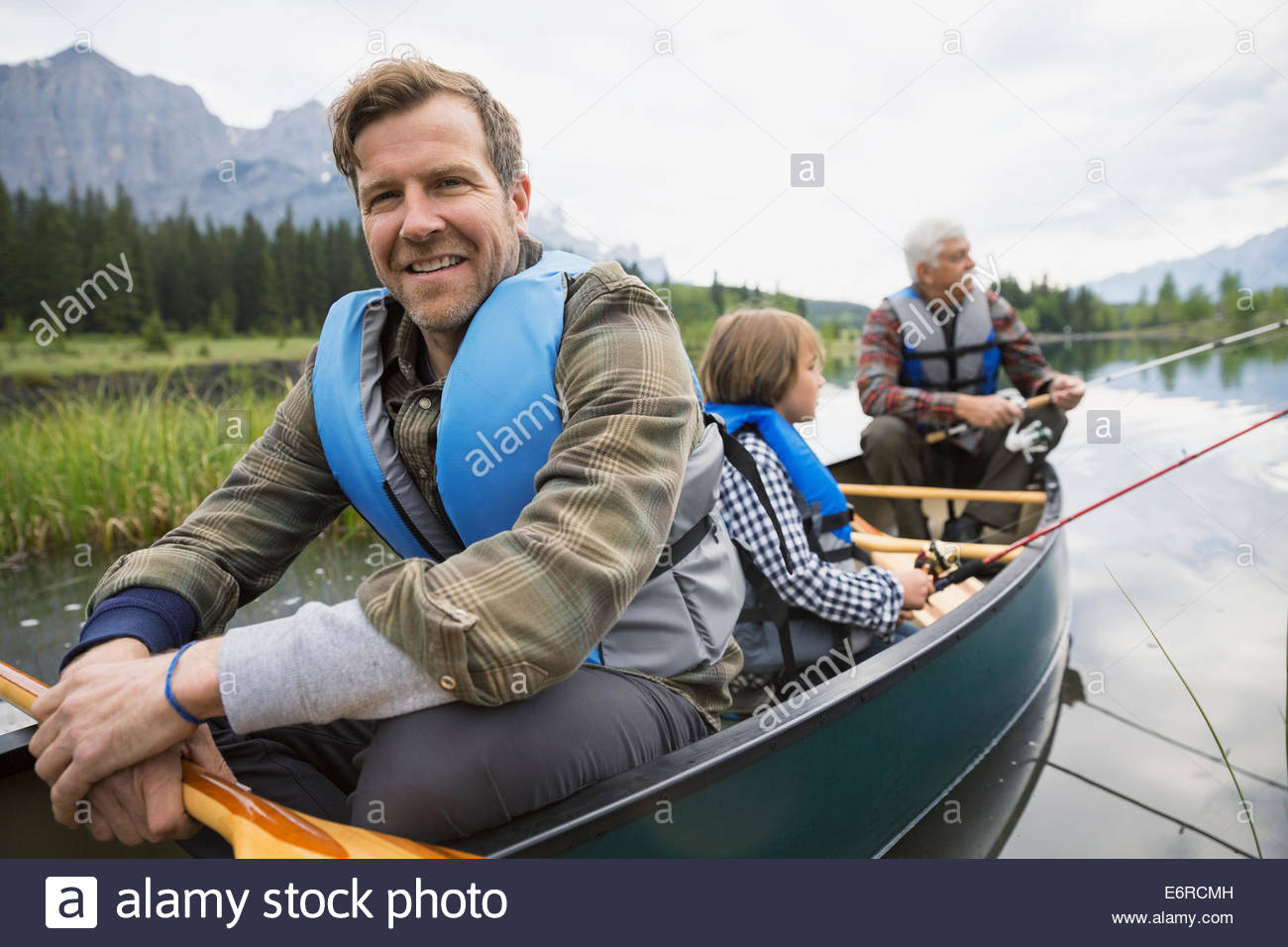 Three generations of men fishing in lake Stock Photo