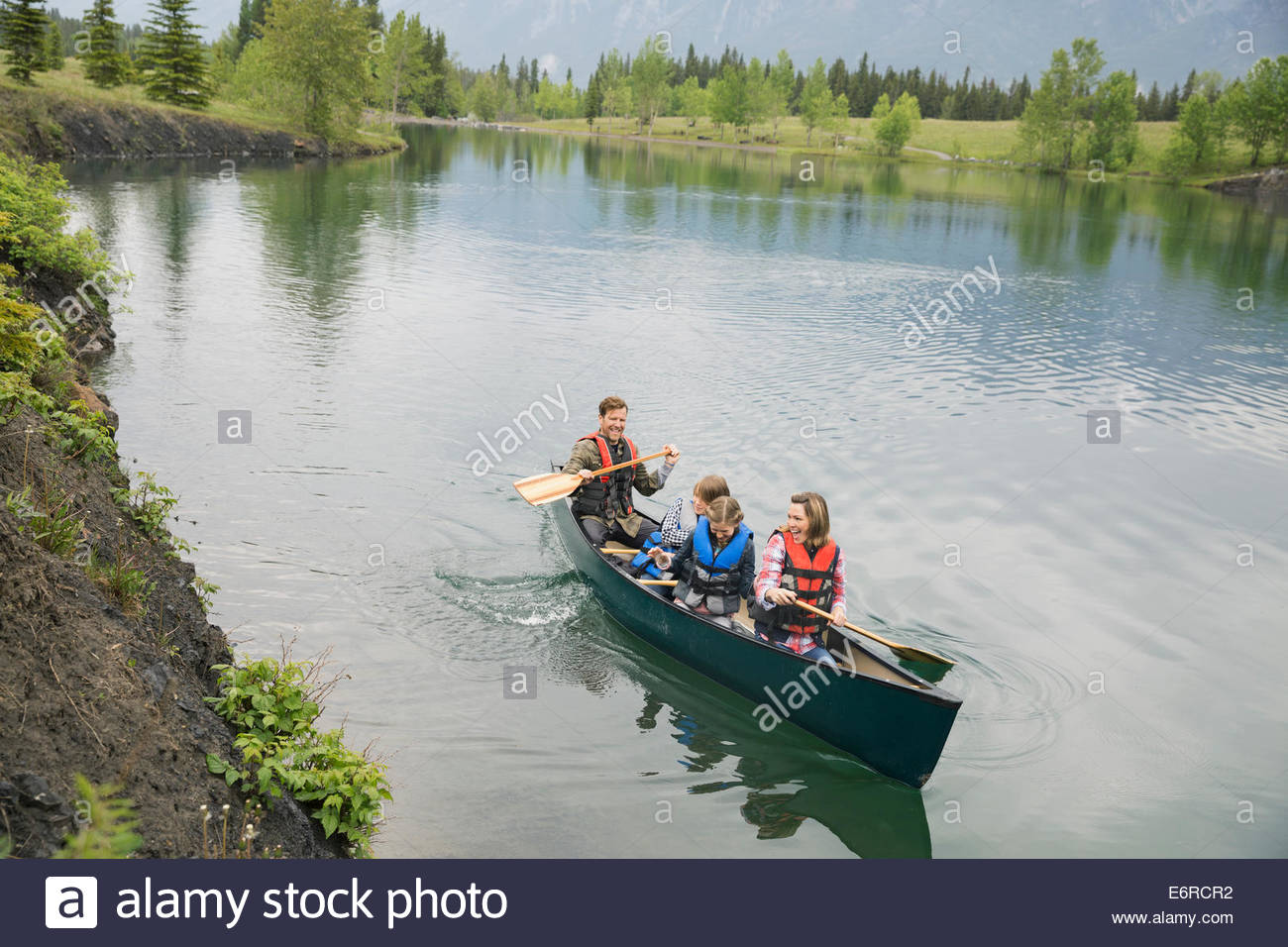 Family rowing canoe in still lake Stock Photo