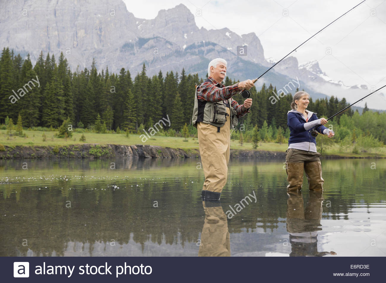 Older couple fishing in still lake Stock Photo