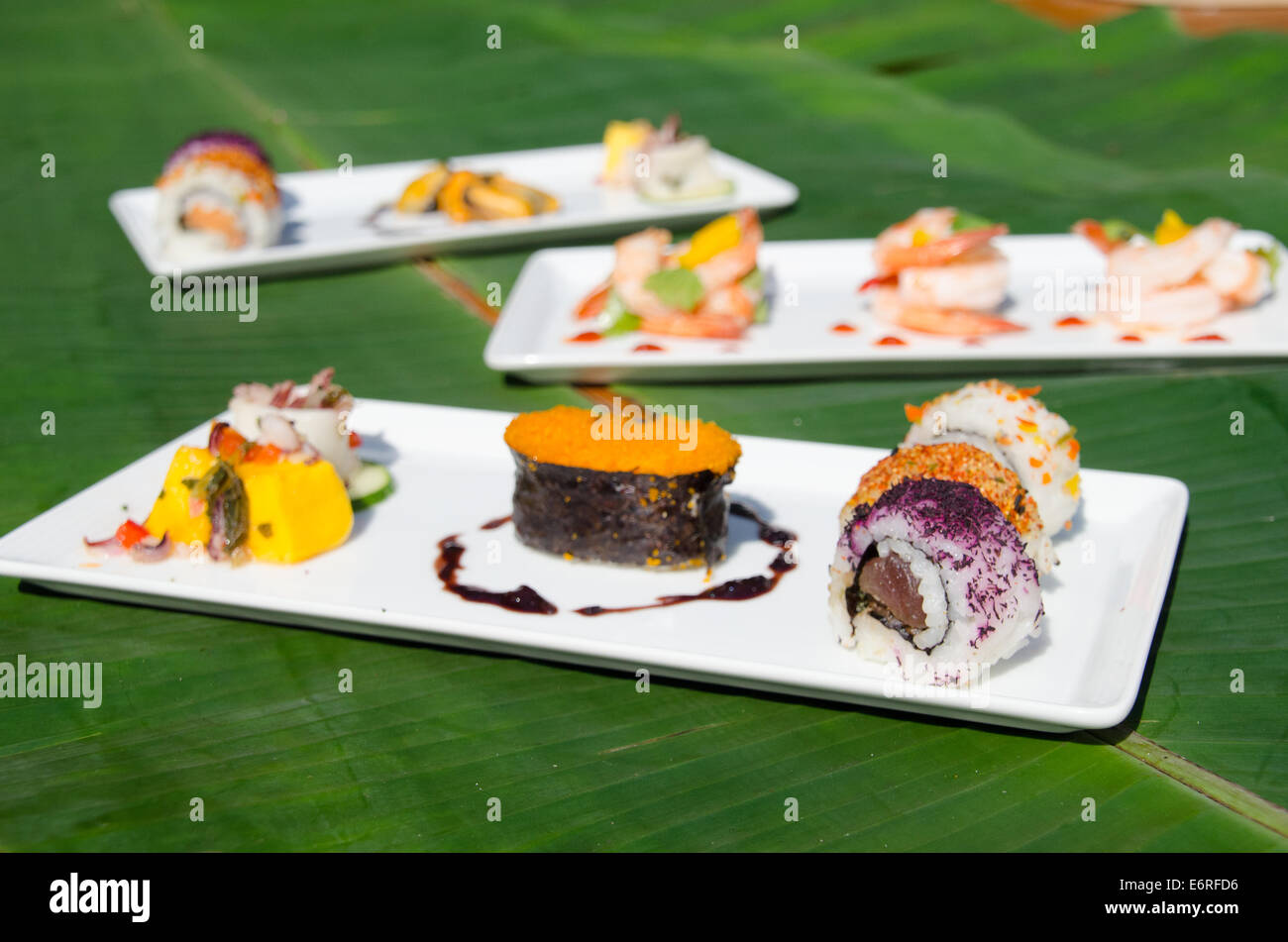 Three trays of small plates for a catered party, including elegantly plated sushi, shrimp and other fish Stock Photo