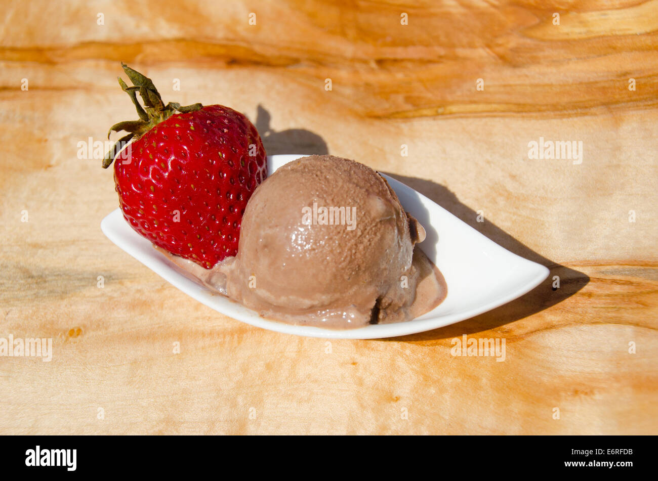 One scoop of chocolate sorbet, gelato or ice cream on a bowl with a strawberry at an outdoor picnic Stock Photo