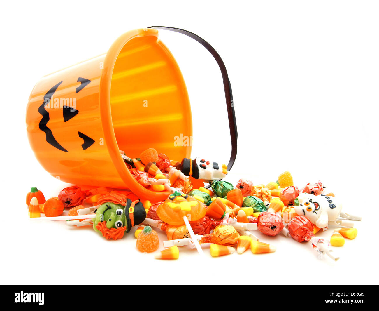 Halloween jackolantern pail with spilling candy over white Stock