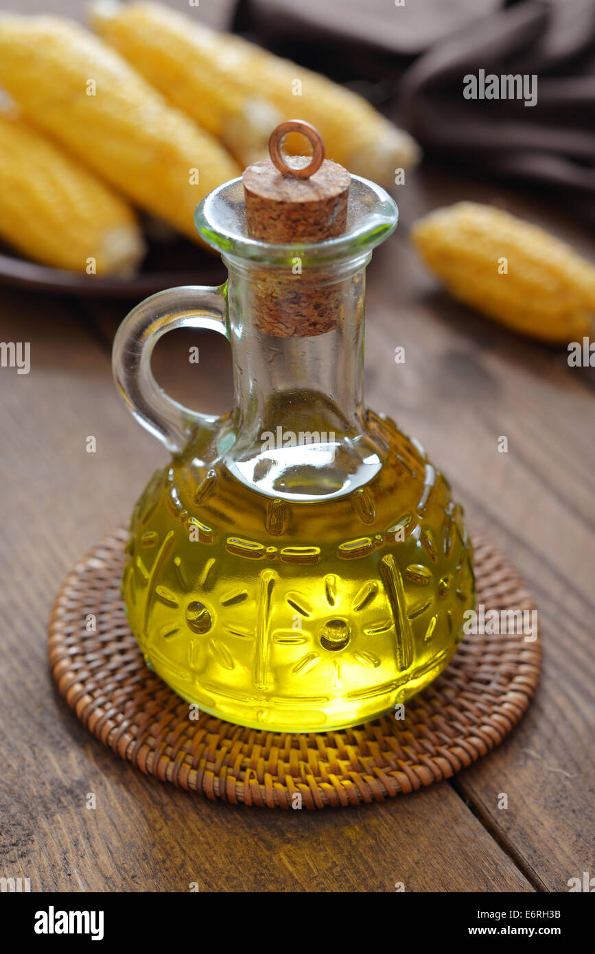 Corn oil in bottle with corn cobs on wooden background Stock Photo