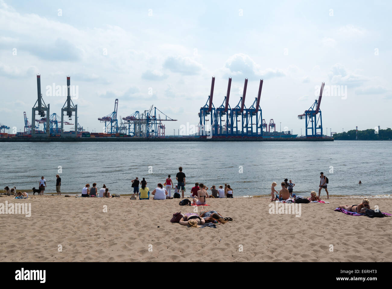 HAMBURG, GERMANY – JULY 21, 2014: People are enjoying summer while sitting and laying on the sandy beach while facing the contai Stock Photo