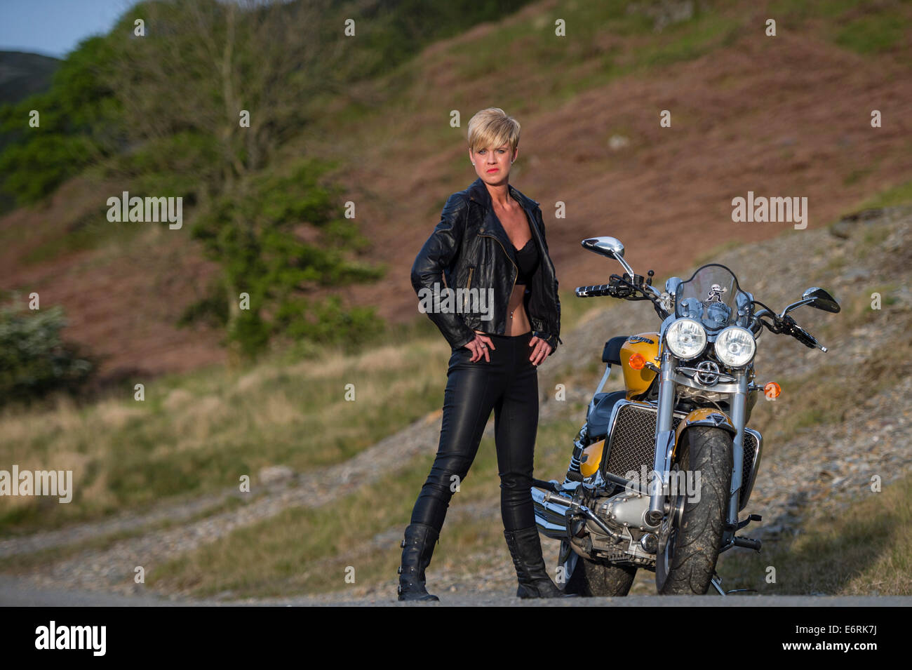 A woman posing with a powerful Triumph Rocket III motorbike for a 'biker chick / chic' makeover photo shoot UK Stock Photo