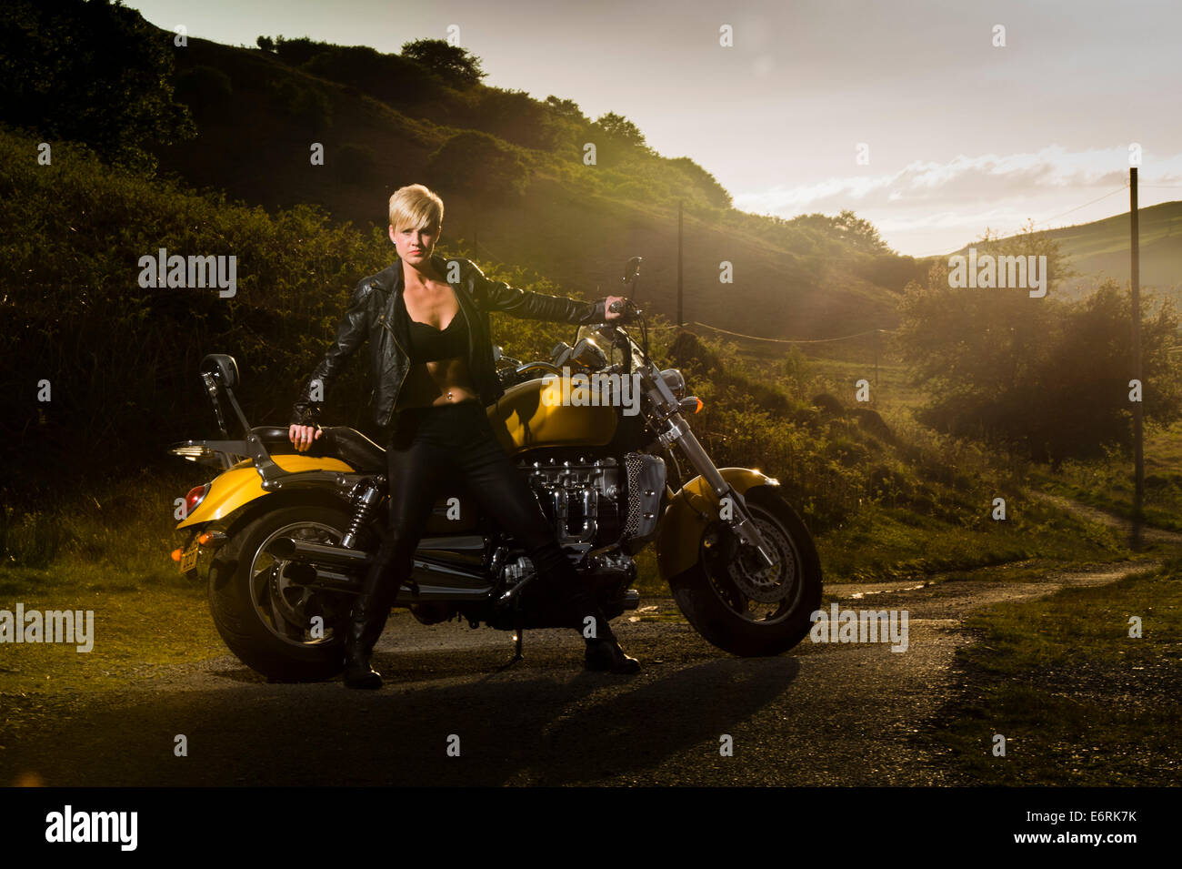 A woman posing with a powerful Triumph Rocket III motorbike for a 'biker chick / chic' makeover photo shoot UK Stock Photo