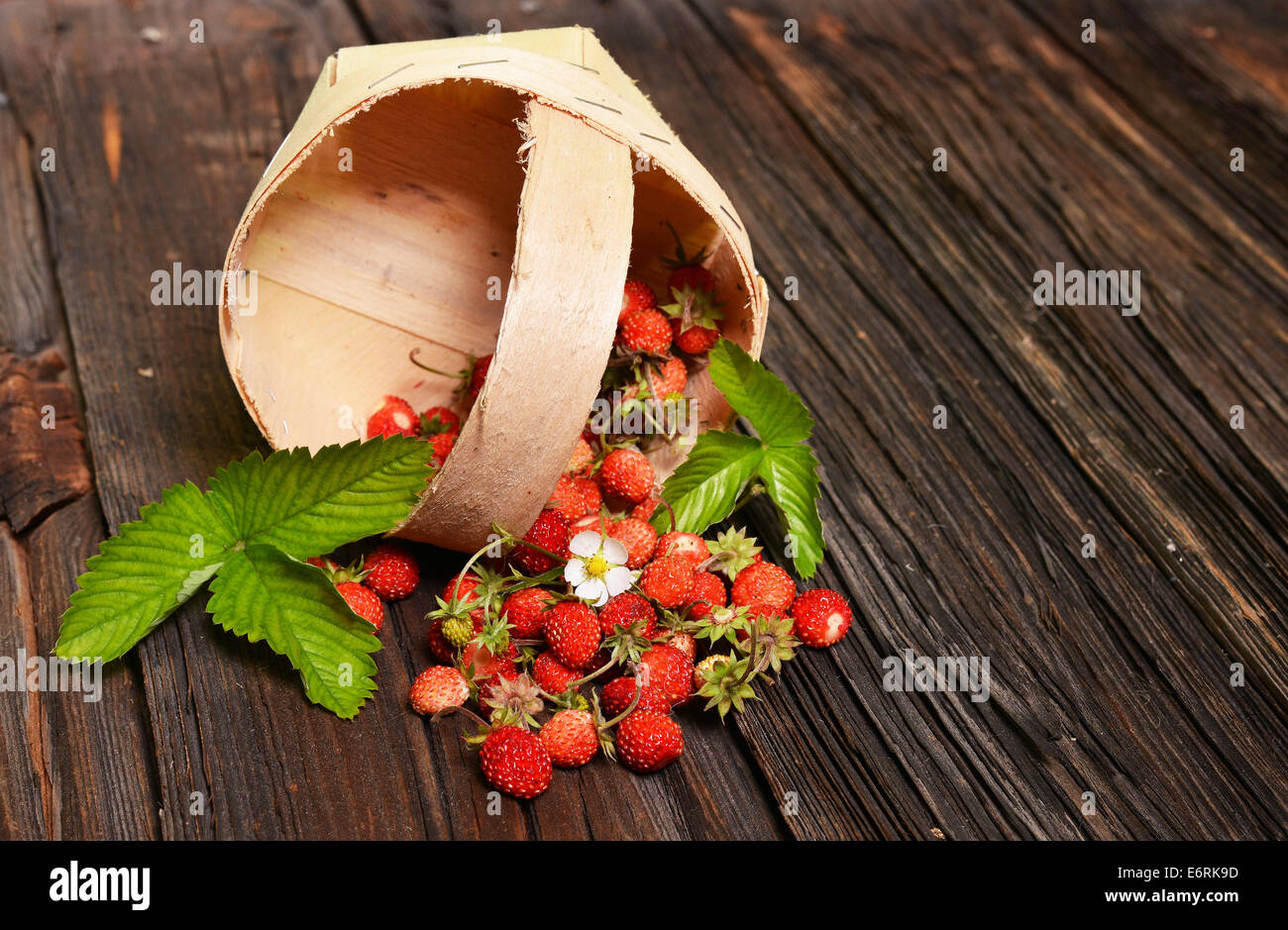 Wild strawberries in backet on old wooden table Stock Photo - Alamy
