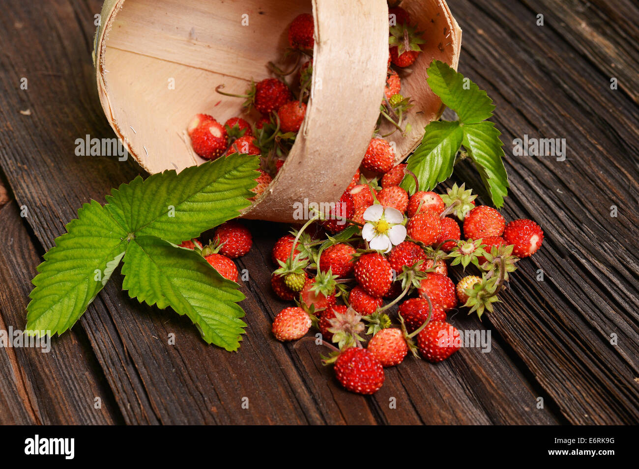Wild strawberries in basket on old wooden table Stock Photo - Alamy