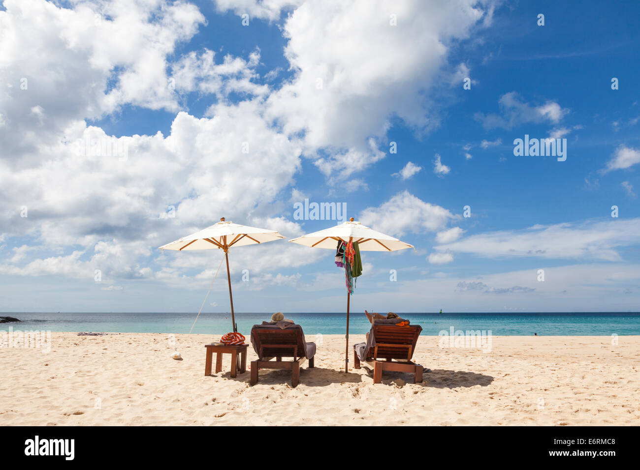 Sunloungers and two sun parasols on the sandy beach at Pansea Beach, Phuket, Thailand with blue sky and white fluffy clouds Stock Photo