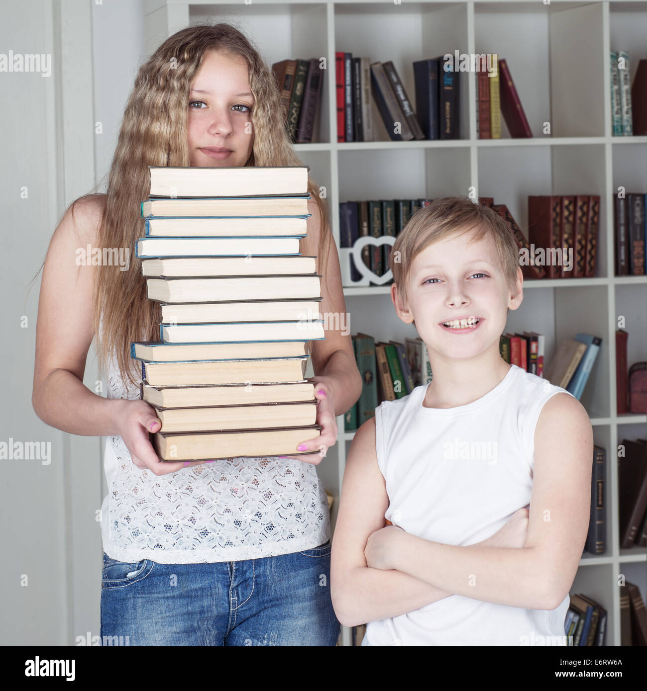 Boy and girl with books standing near a bookcase Stock Photo - Alamy