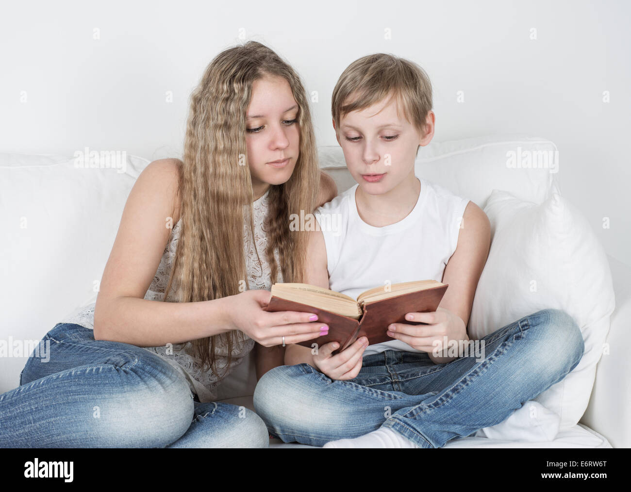 Читал с сестрой читал с ней. Сестра читает уроки. Мальчик и девочка сидят вместе читая книгу.