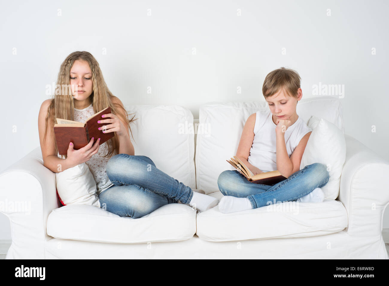 Boy and girl sitting on the couch and read a book Stock Photo