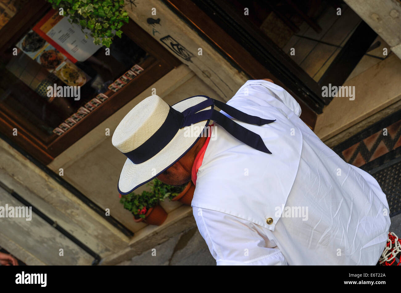 Traditionally dressed Venetian Gondola wearing white hat. Stock Photo