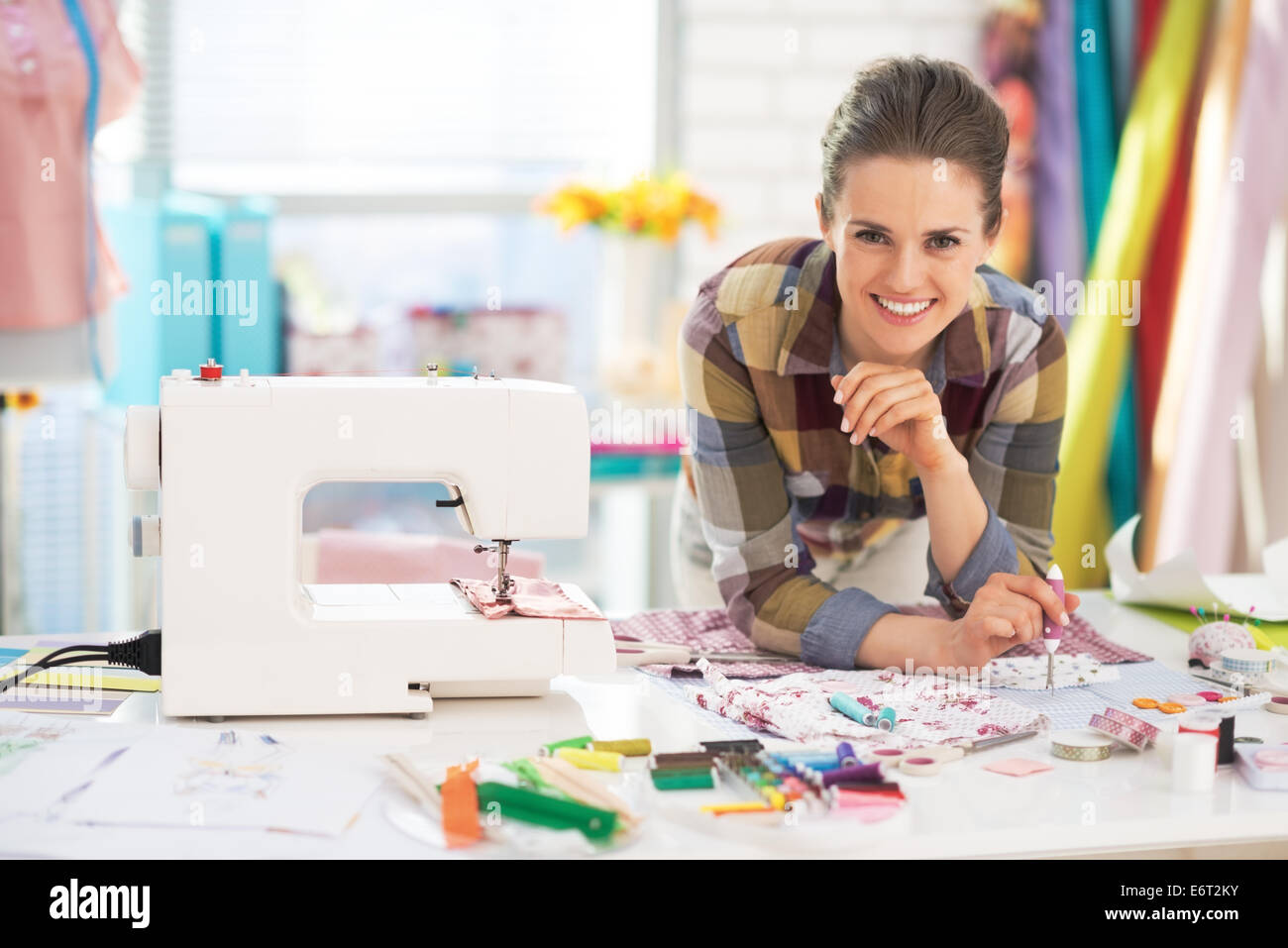 Portrait of smiling tailor near sewing machine Stock Photo - Alamy
