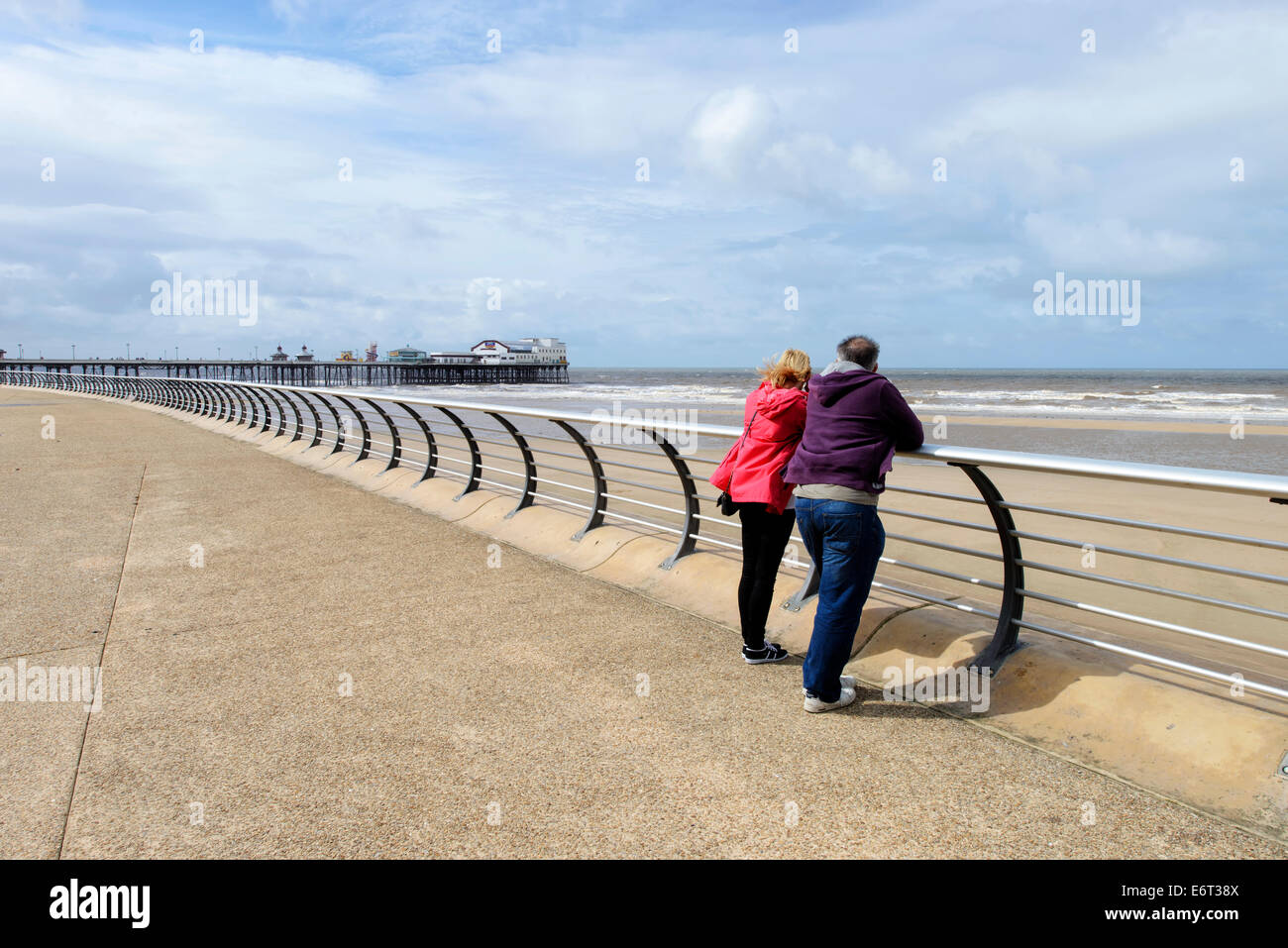 Middle aged couple on the promenade in Blackpool looking out to sea. North Pier is in the background Stock Photo