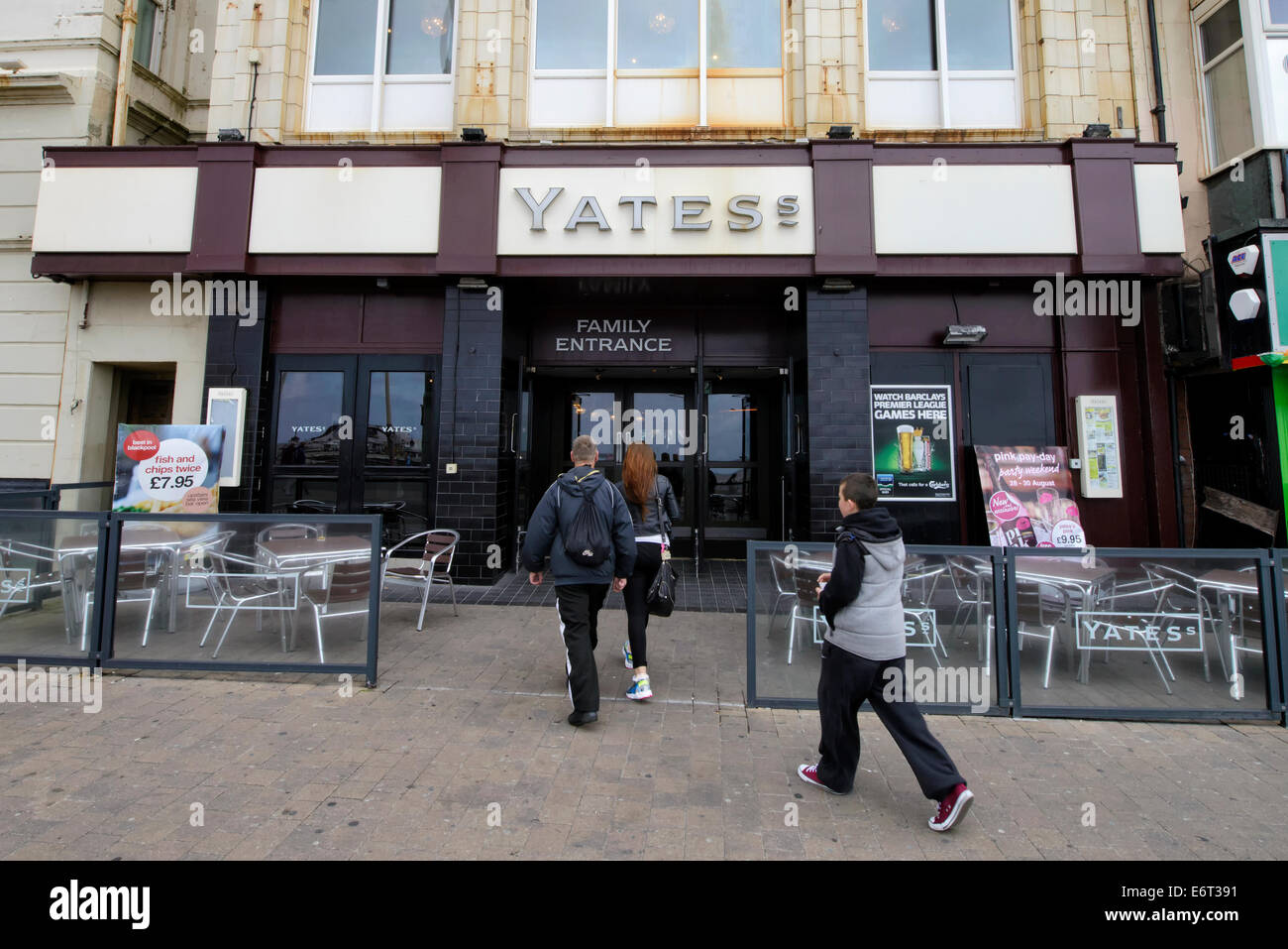 Mum, Dad and young person entering a branch of Yates in Blackpool, Lancashire Stock Photo