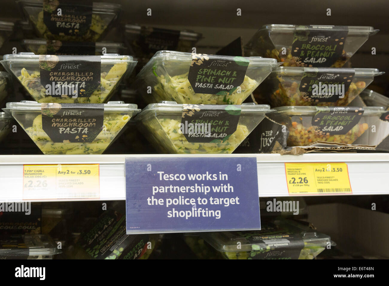 Signs on shelves in a Tesco supermarket advising customers that Tesco works in partnership with the Police to target shoplifters Stock Photo