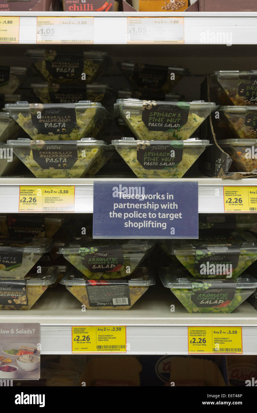 Signs on shelves in a Tesco supermarket advising customers that Tesco works in partnership with the Police to target shoplifters Stock Photo