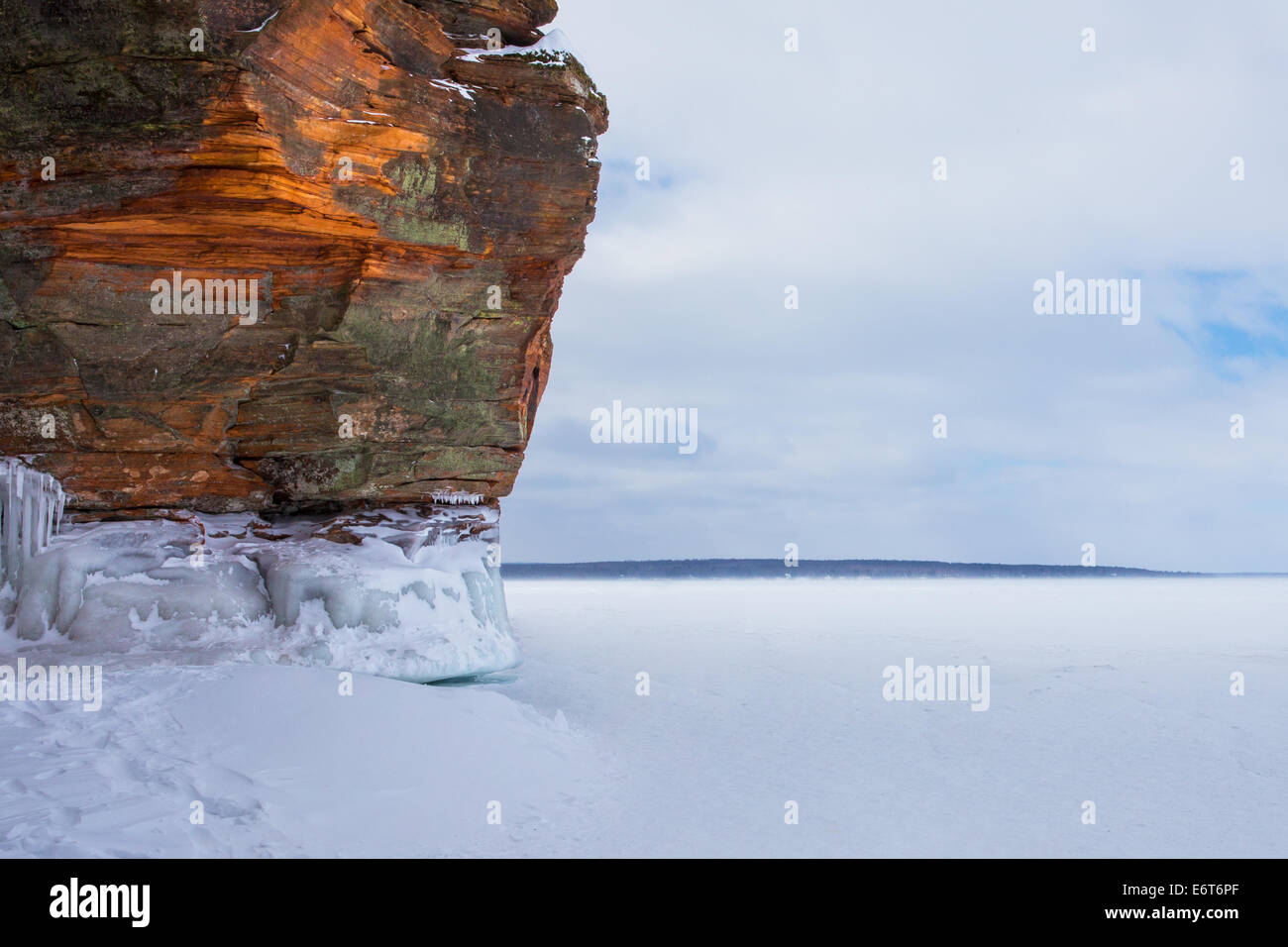 Warm light on rocky cliff / shoreline of a frozen Lake Superior.  Highly textured rock.  Lots of copy space to the right. Stock Photo