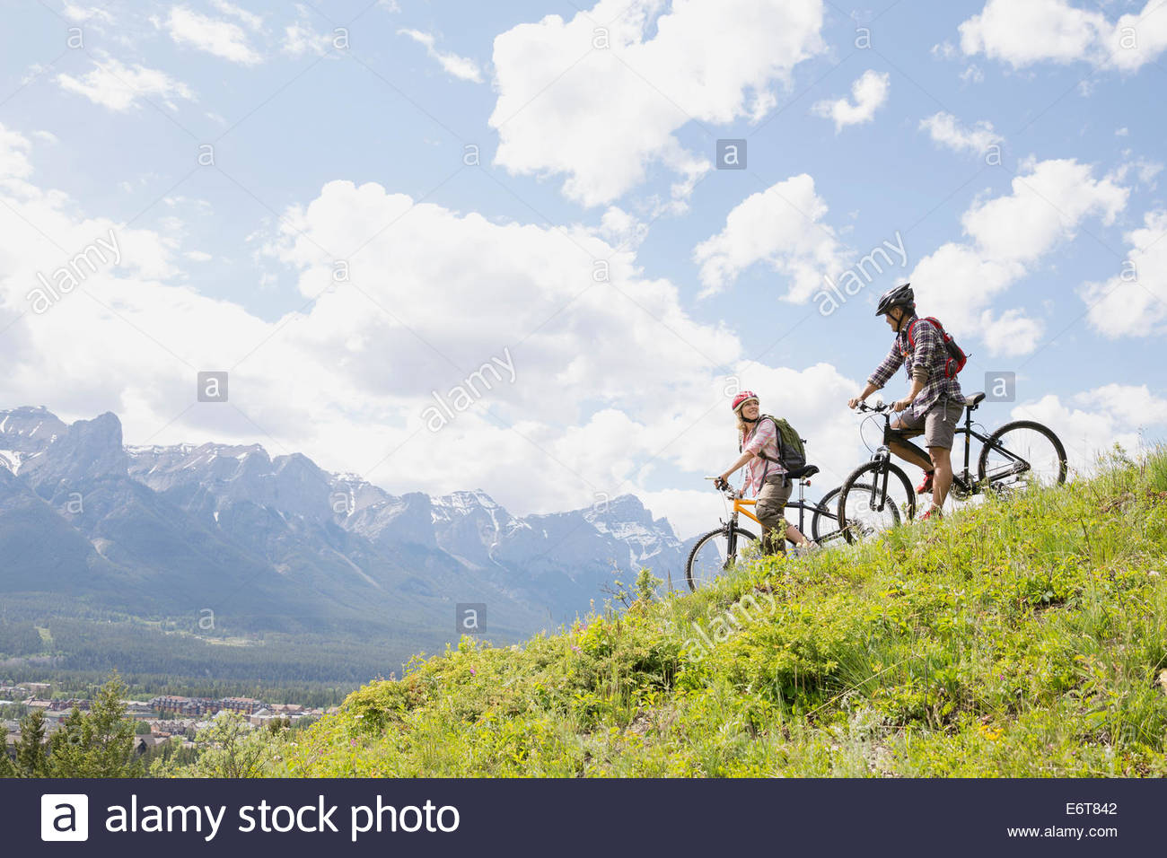 Couple standing with mountain bikes on hillside Stock Photo