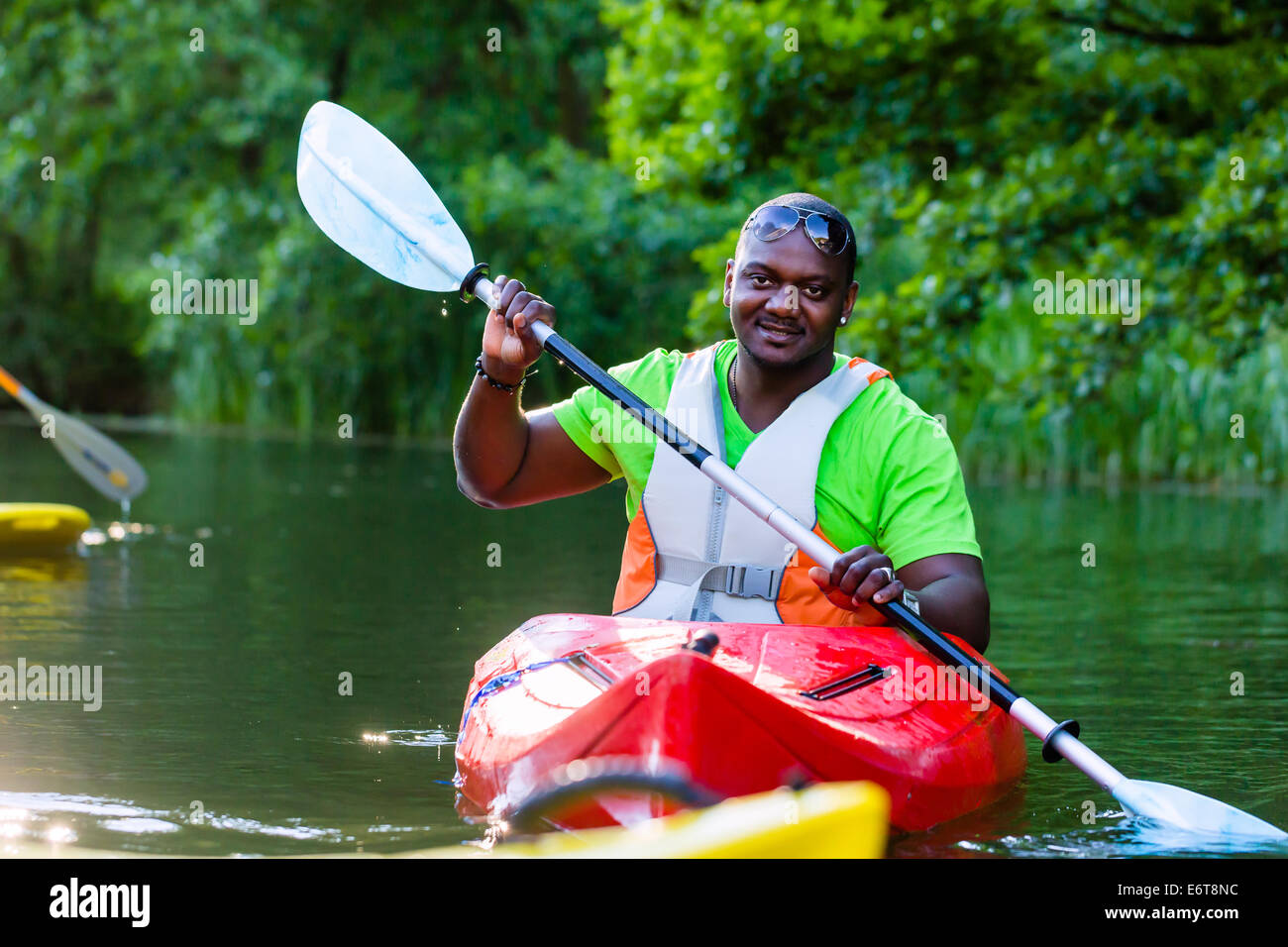 African Man paddling with canoe on forest river Stock Photo