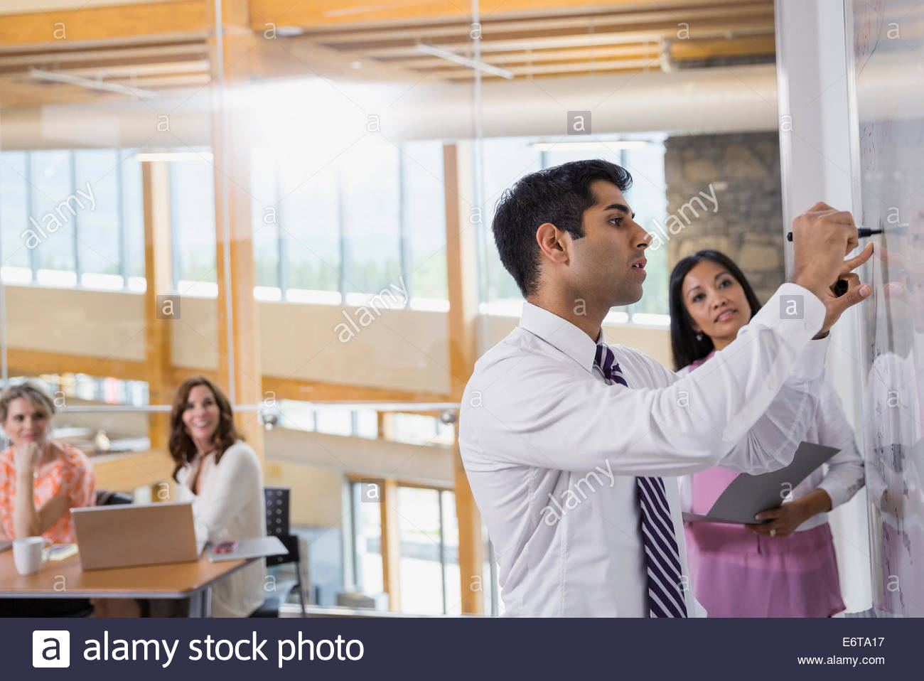Businessman writing on white board in meeting Stock Photo