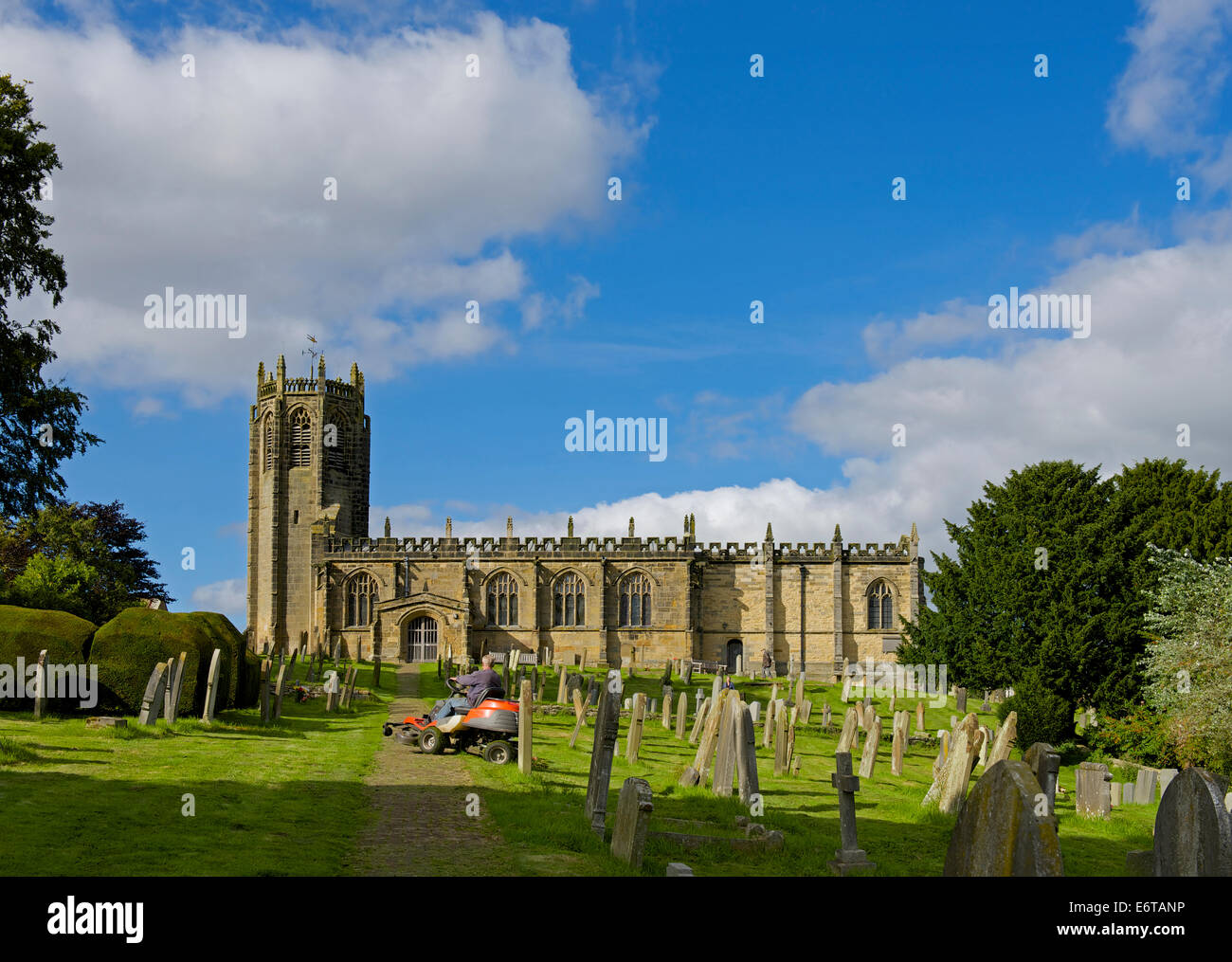 Cutting the grass at St Michael's Church, in the village of Coxwold, North Yorkshire, England UK Stock Photo