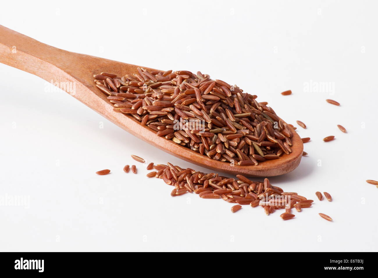 Red rice in a wooden spoon on white background Stock Photo - Alamy