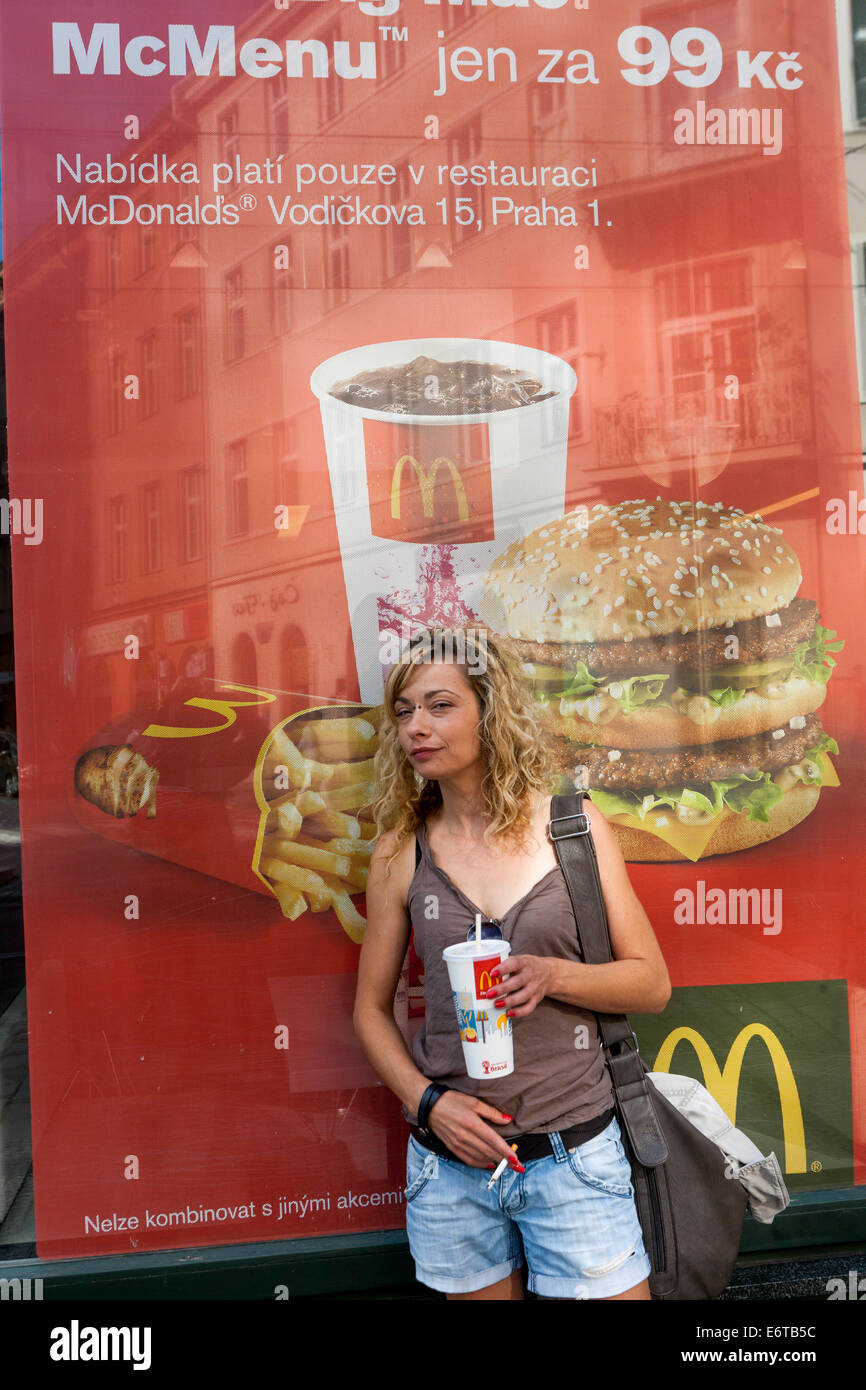 A woman outside McDonald's advert fast food Poster, window display, Prague, Czech Republic McDonald's woman Stock Photo