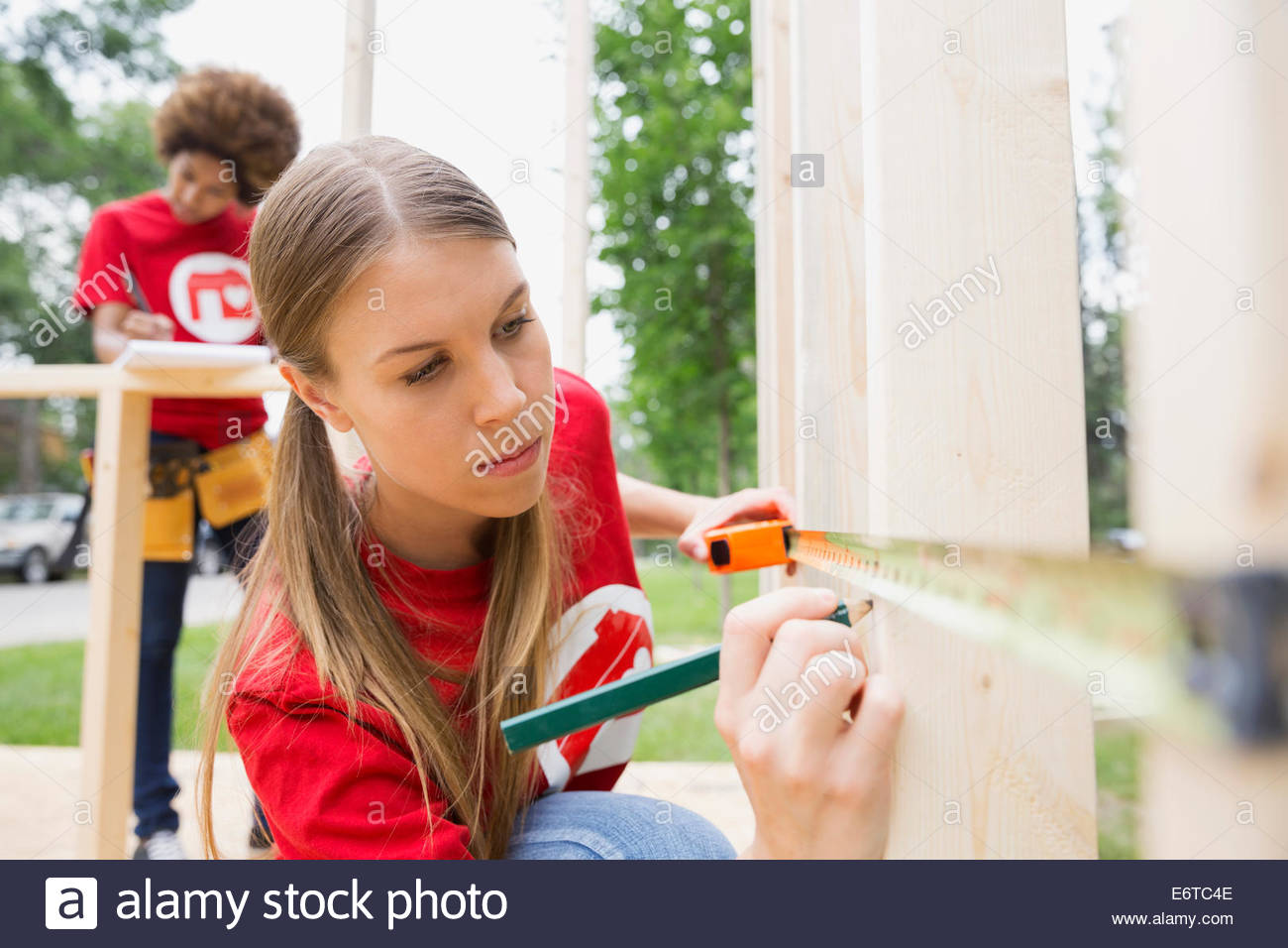 Volunteer measuring construction frame with tape measure Stock Photo