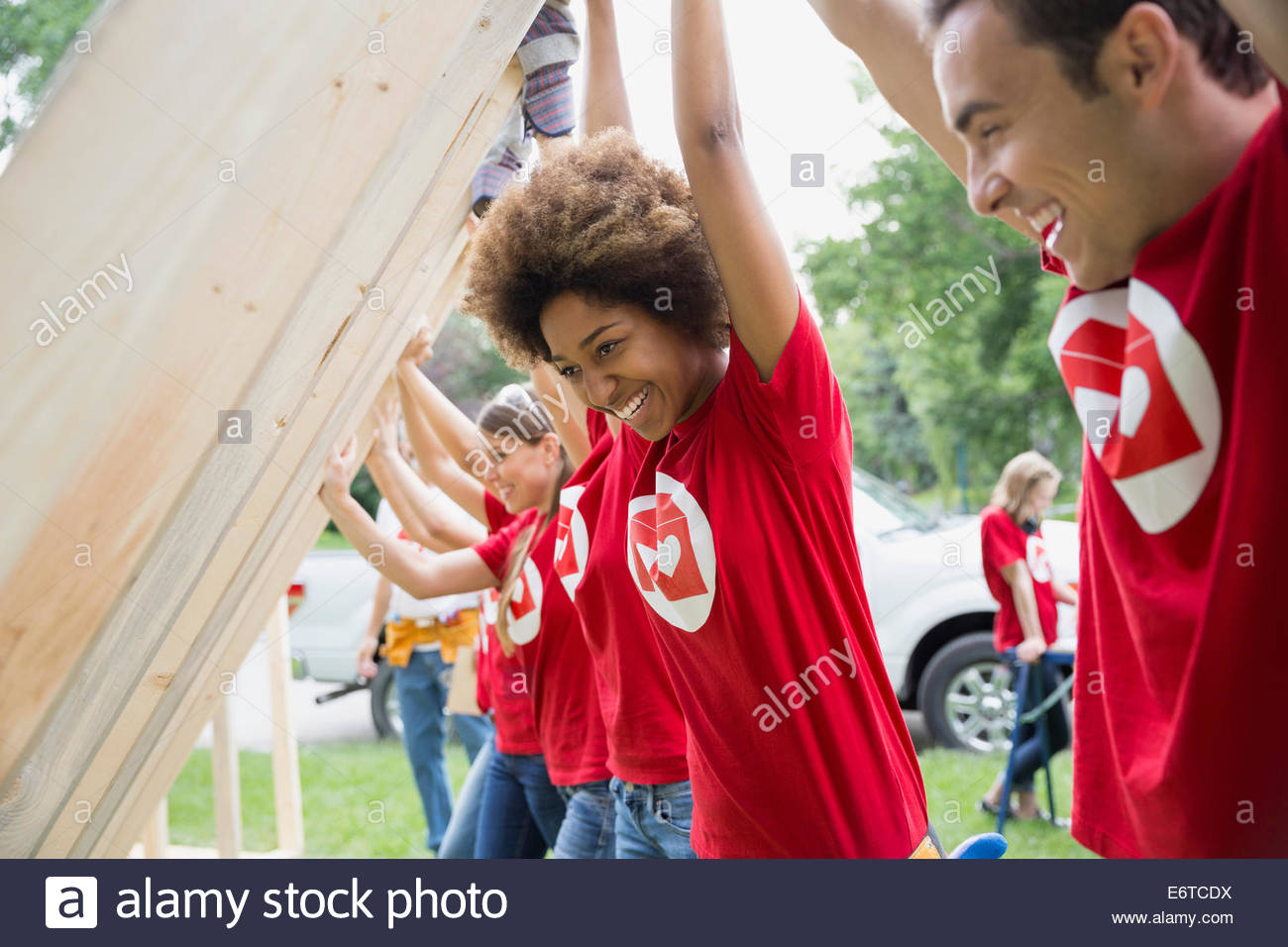 Smiling volunteers lifting construction frame Stock Photo