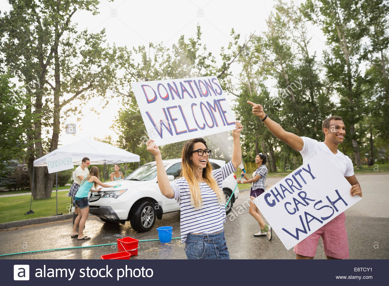 Enthusiastic volunteers waving charity car wash signs Stock Photo