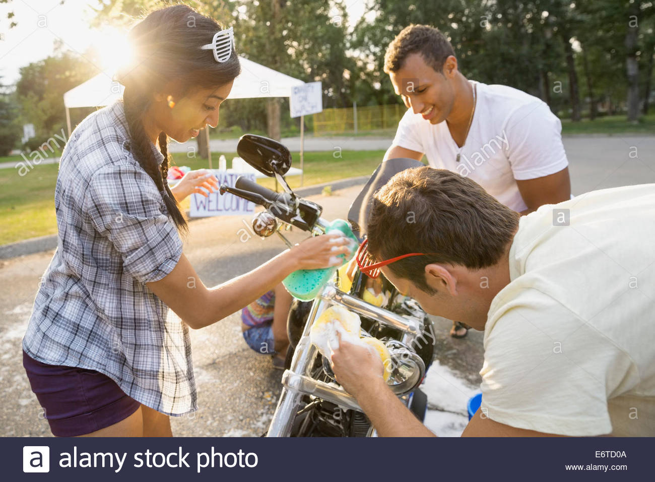 Friends washing motorcycle at charity car wash Stock Photo