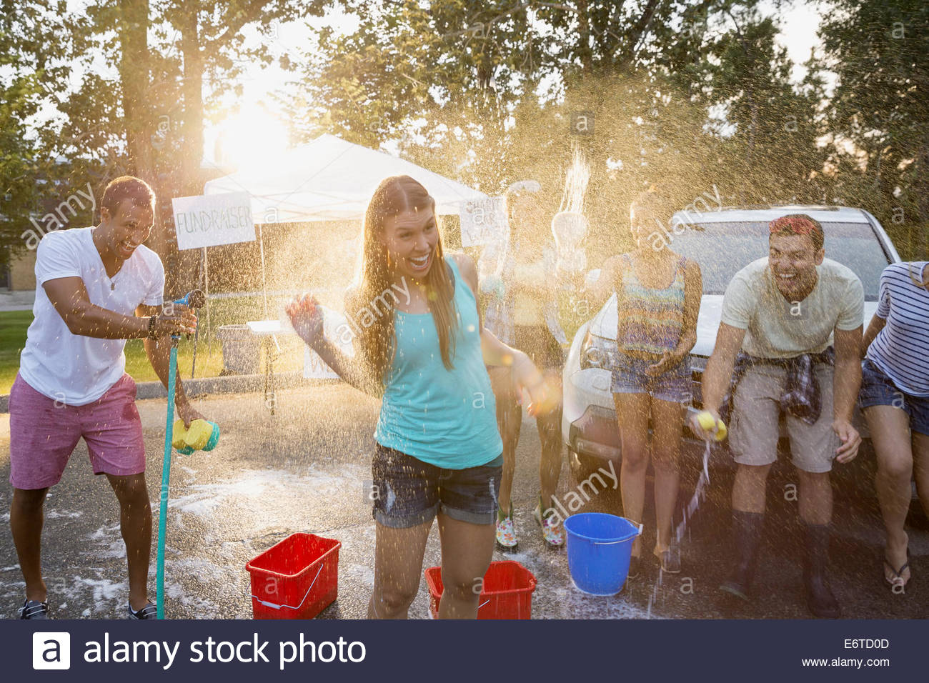 Man spraying woman with hose at car wash Stock Photo