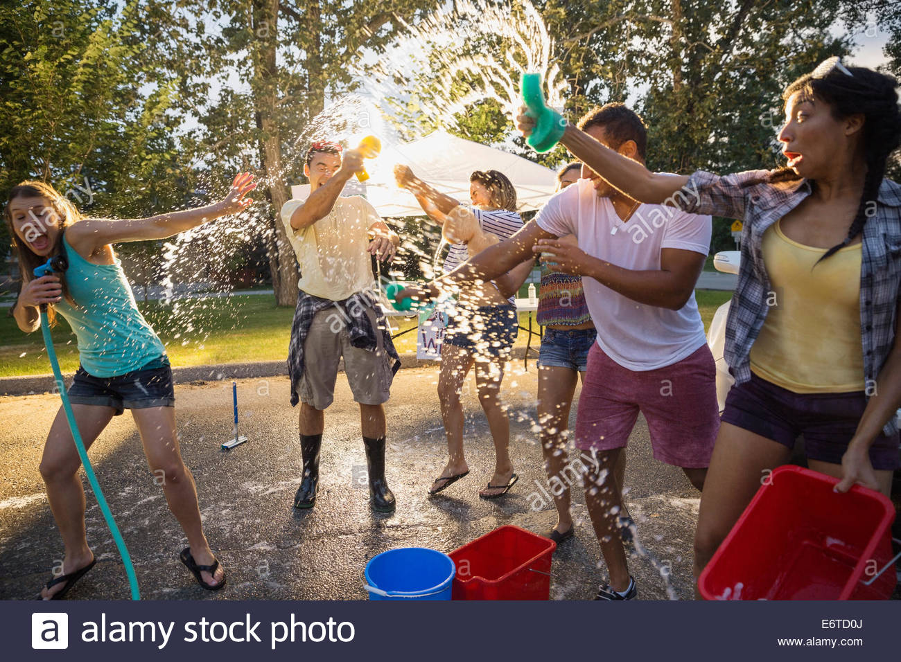Playful friends splashing at charity car wash Stock Photo